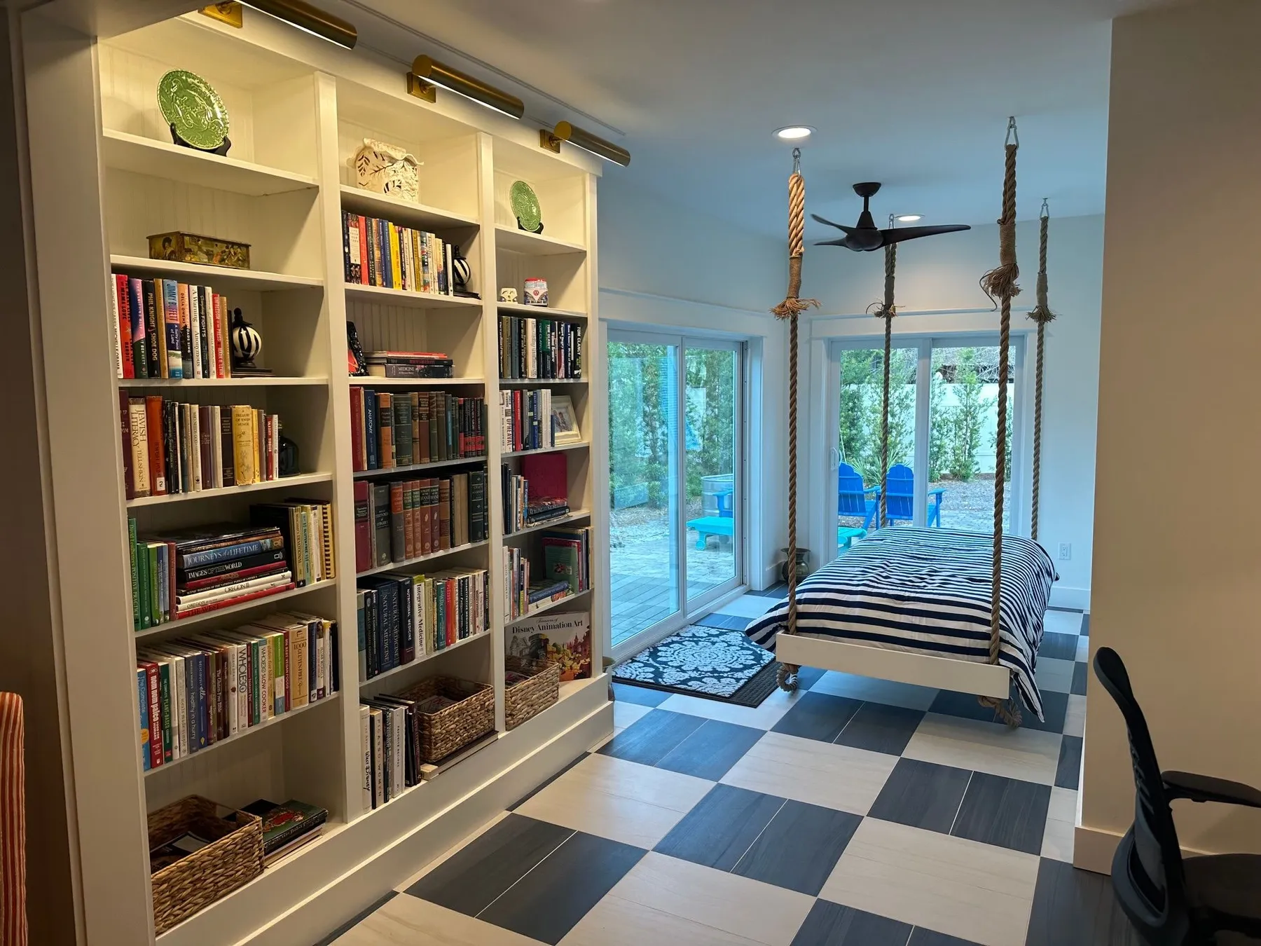 Remodeled porch with a lit built-in bookcase, a hanging bed on ropes, sliding glass doors, and a checkerboard tile floor.